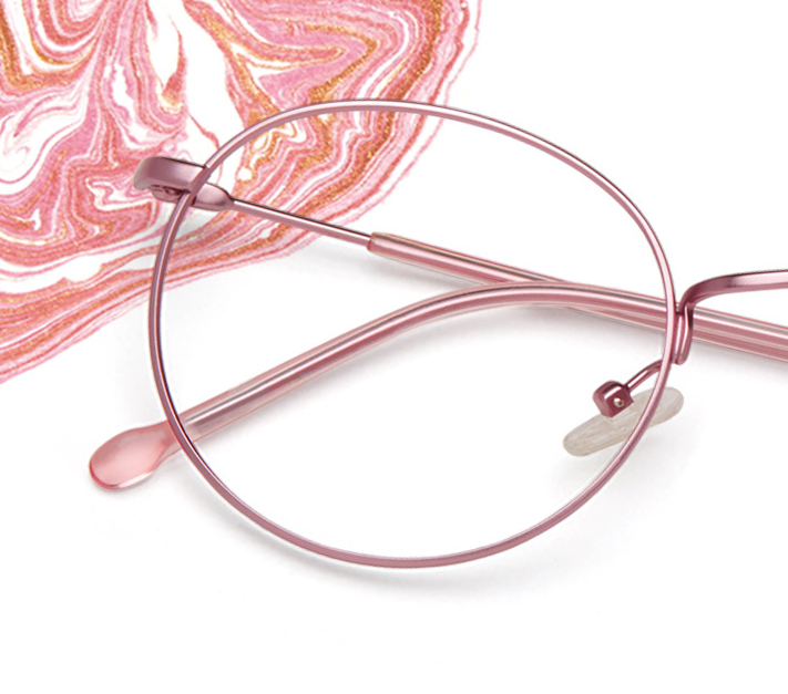 Pink metal round eyeglasses on a white surface with a pink and white swirl pattern in the background.