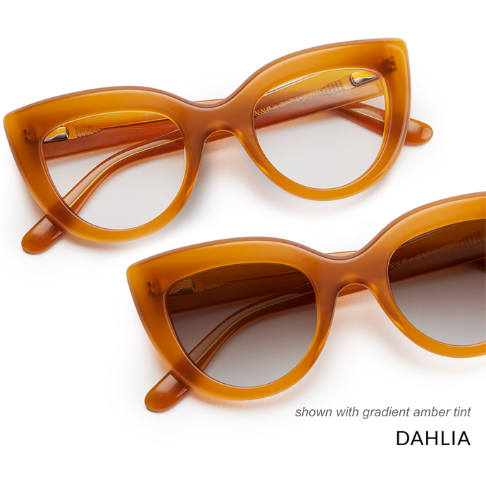 Amber-tinted cat-eye sunglasses with thick frames, shown with gradient amber tint. "DAHLIA" text included.