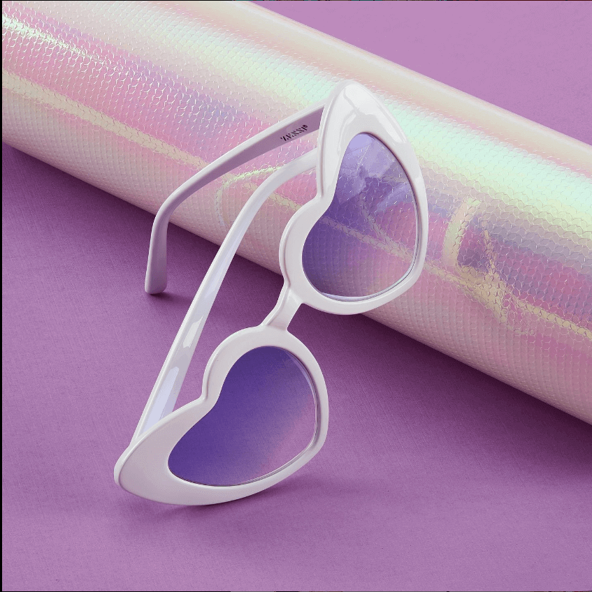 Heart-shaped white frame sunglasses with purple lenses. Brand name DIOR printed on the temple.