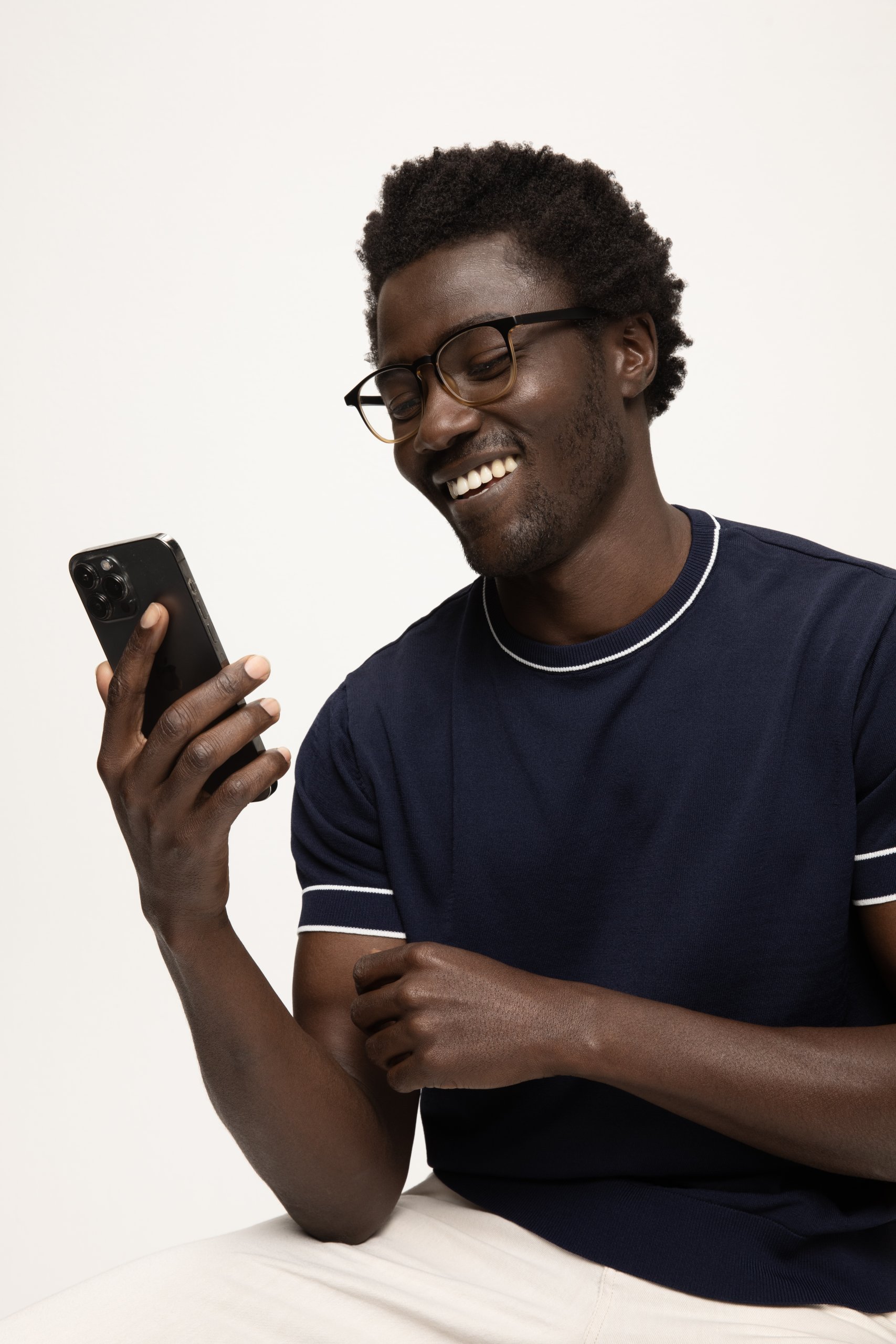 Person smiling while holding a black smartphone with triple-lens camera.
