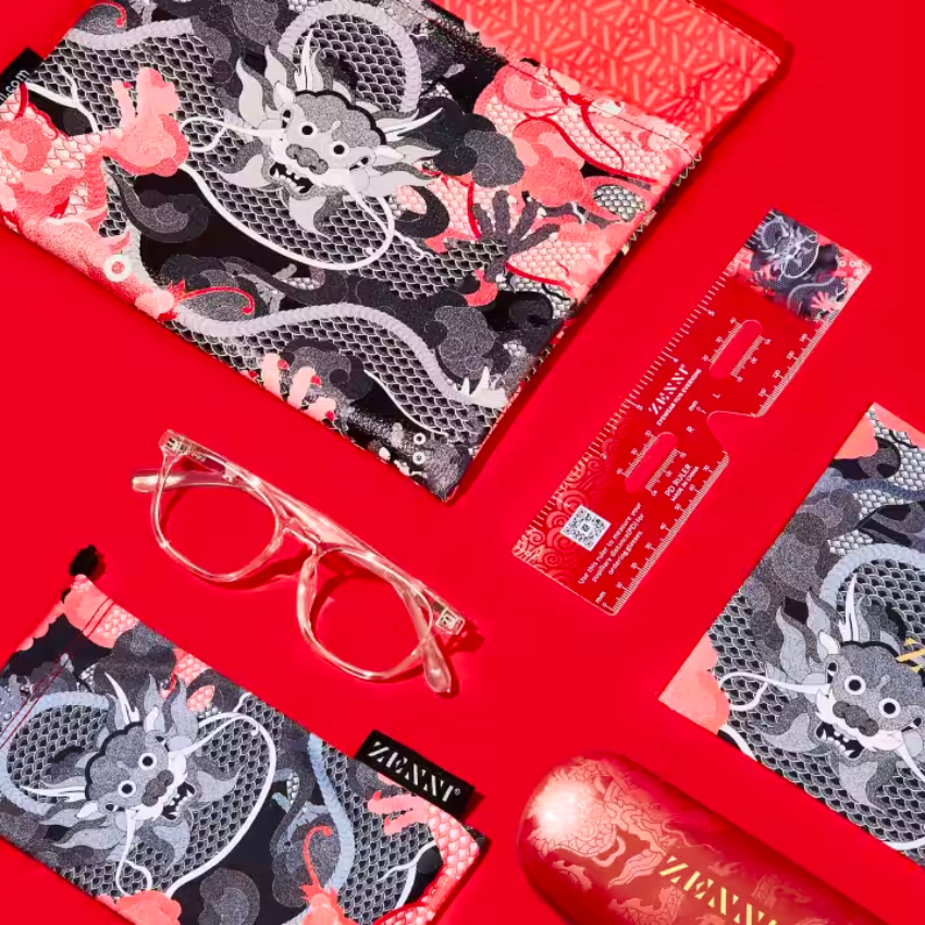 Zenni glasses with transparent frame, dragon-patterned cases, and a red ruler showing Zenni logo and QR code.