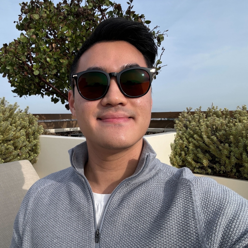 Man wearing black sunglasses and a light gray zip-up sweater.