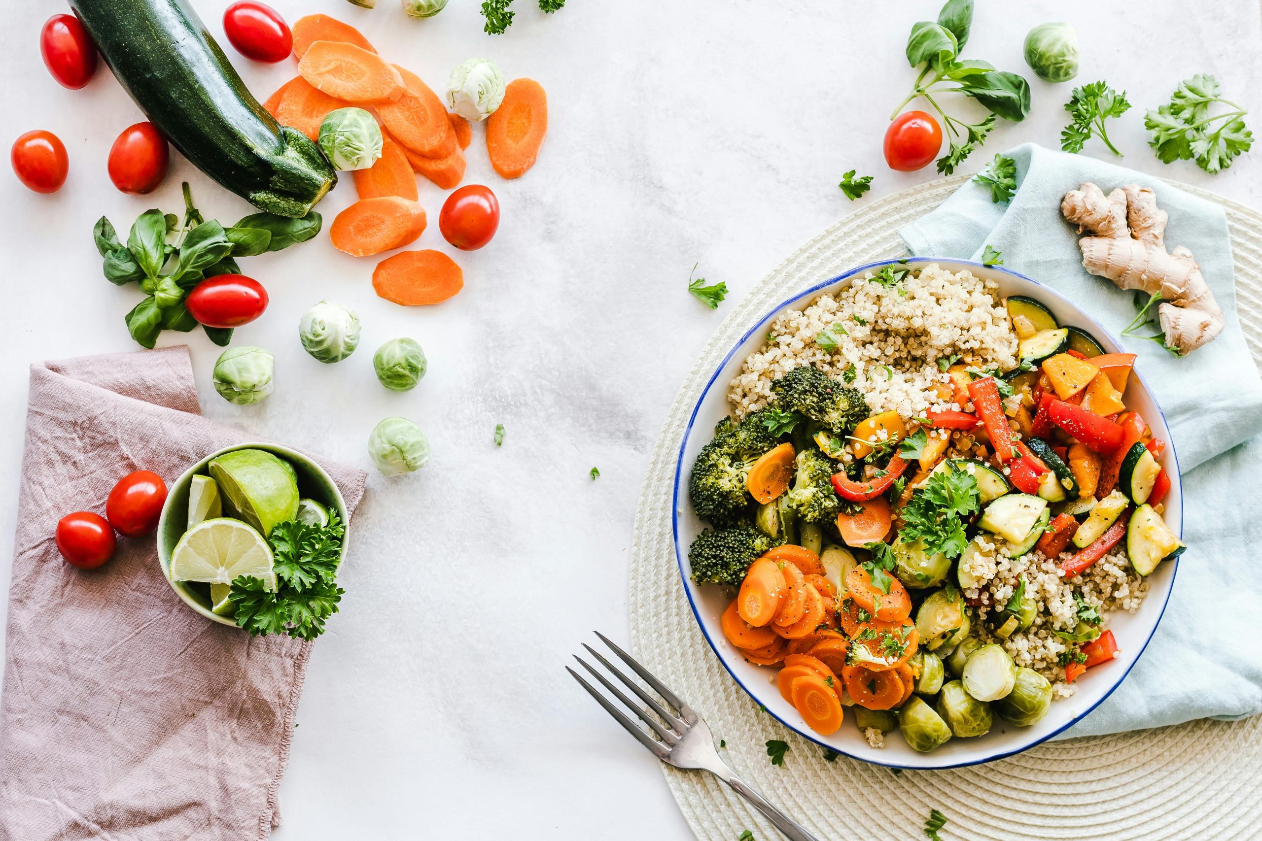 Bowl of quinoa with mixed vegetables, including broccoli, carrots, zucchini, bell peppers, and brussels sprouts.
