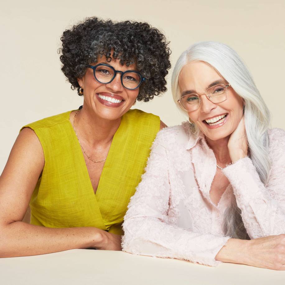 Two women wearing fashionable eyeglasses, smiling and posing.