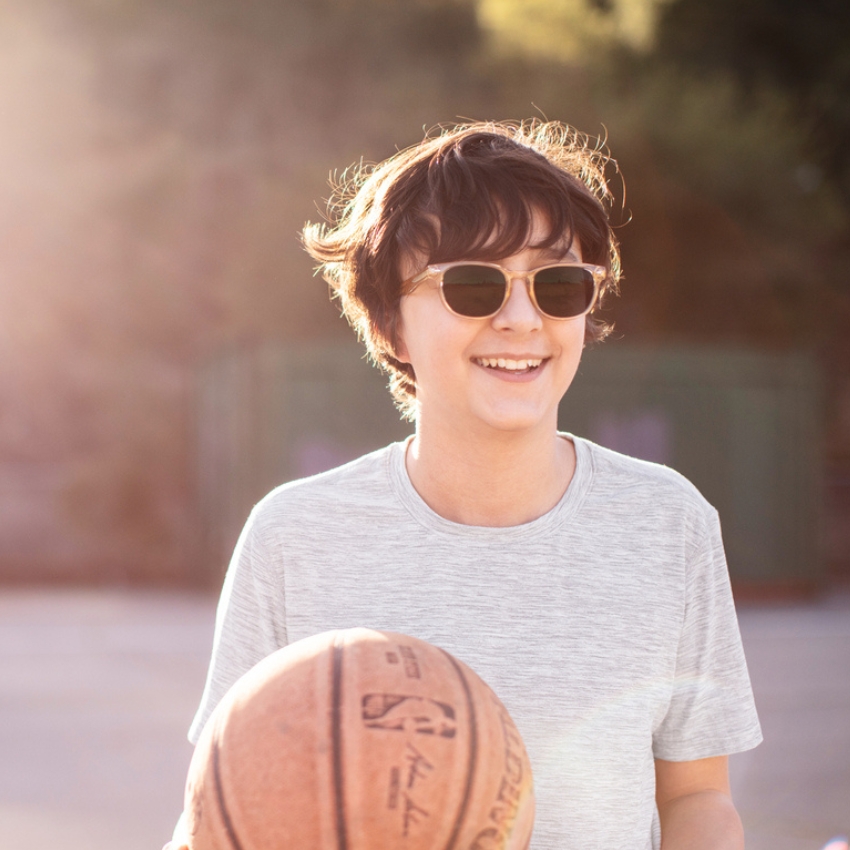 Person wearing sunglasses, holding a basketball with the logo and text "NBA Spalding Indoor/Outdoor".