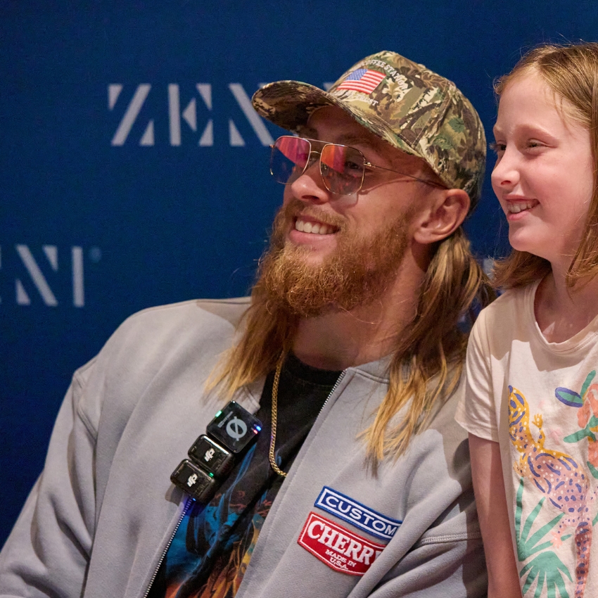 Person in camo cap and sunglasses; jacket with "Custom Cherry Electric Beach '23" patch.